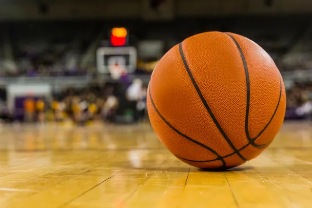 A basketball is on the court with people watching.