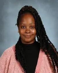 A woman with long braids wearing a pink sweater.