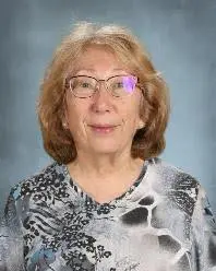 A woman with glasses and a floral shirt.