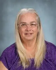 A woman with long blonde hair wearing glasses.