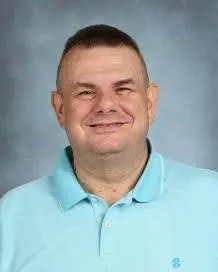 A man with a shaved head and blue shirt.