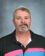 A man with grey hair and beard wearing a black shirt.