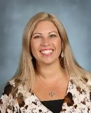 A woman with long blonde hair and a brown shirt.