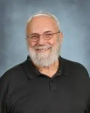 A man with white beard and glasses is smiling.