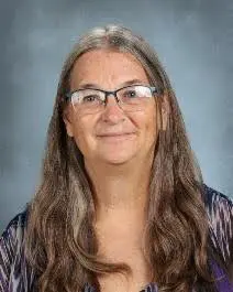 A woman with long hair wearing glasses and smiling.