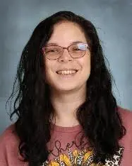 A woman with long hair and glasses smiling.